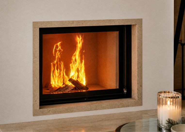 Detaillierter Blick auf das lodernde Holzfeuer hinter der Sichtscheibe, die von einem edlen Sandsteinrahmen eingefasst ist.