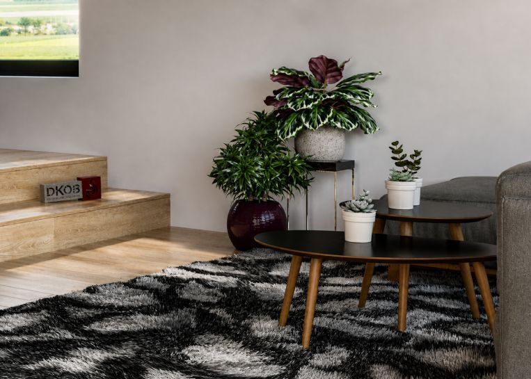 Detailansicht der Wohnraum-Dekoration mit Pflanzen und Beistelltischen, die das moderne Ambiente der Gaskaminanlage ergänzen.