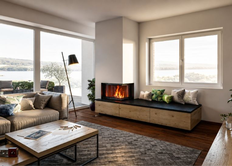 Deckenhoher, weiß verputzter Speicherofen mit großer Eck-Sichtscheibe, dunkler Natursteinbank und Holz-Unterschränken im Wohnzimmer.