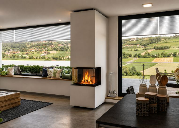 Perspektive auf den deckenhohen Kaminbau im offenen Wohn-Essbereich mit Fokus auf die elegante Integration in die moderne Architektur.