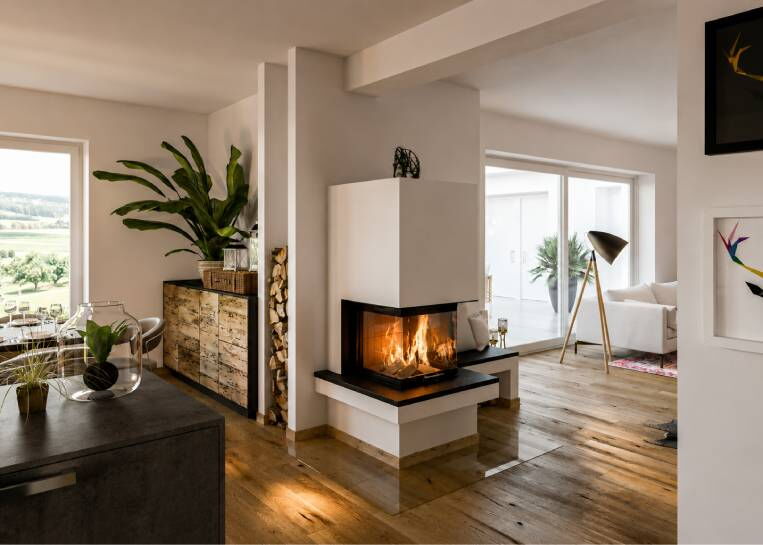 Perspektive auf den Kaminbau, der als eleganter Raumteiler fungiert, mit Blick auf das angrenzende Holzlager und die Küche.