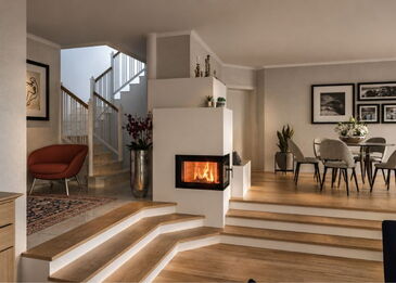 Ein schlichter, weißer Kombiofen mit Eckscheibe, integriert in eine moderne Wohnlandschaft mit Holzstufen und Essbereich.
