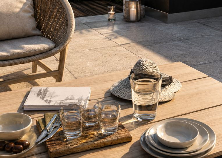Nahaufnahme einer gedeckten Tafel auf der Terrasse im Vordergrund der Außenküche, die das gesellige Ambiente unterstreicht.
