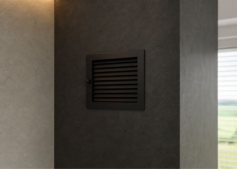 Detailansicht der in die schwarze Fresco-Spachtelung integrierten Revisionsklappe, die das schlichte Design der Anlage unterstreicht.