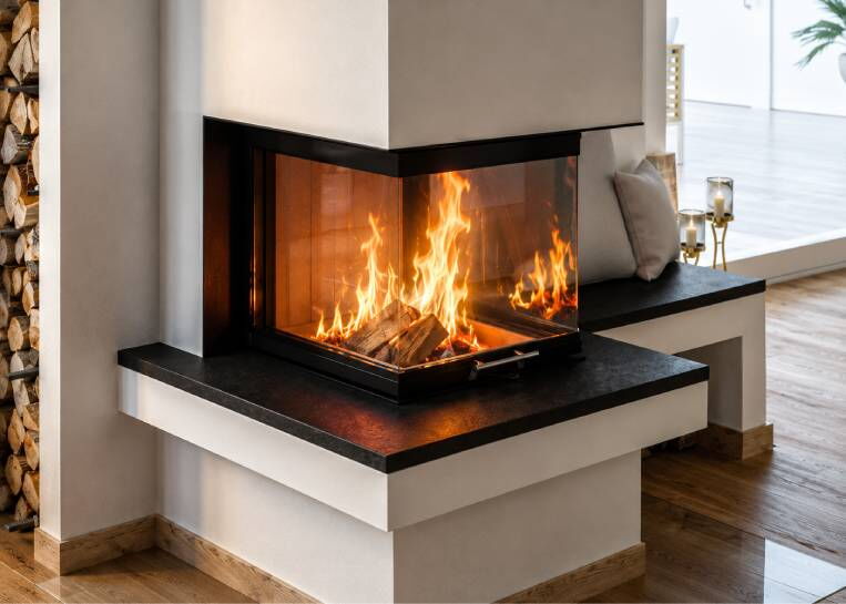 Nahaufnahme der 3-seitigen Verglasung des Spartherm Kamin mit dem 3 cm starken, dunklen Naturstein-Feuertisch.