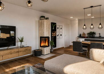 Gesamtansicht eines hellen Eck-Kaminofens aus Travertin-Naturstein in einem modernen Wohnzimmer mit offener Küche.