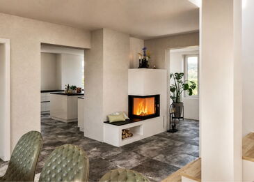 Ein moderner, weiß verputzter Eckkamin mit Spartherm Varia 2L-55 Einsatz, schwarzer Sitzbank und bündig integriertem Holzlager im Sockel.