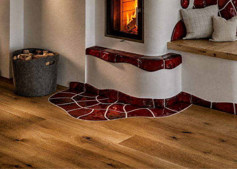 Detaillierte Ansicht des brennenden Holzfeuers hinter der Glasscheibe, umrahmt von strukturierter Handkeramik.