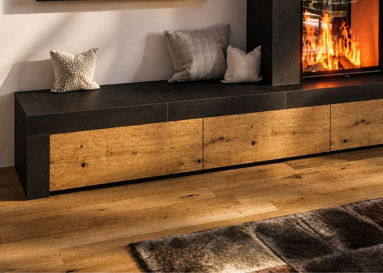 Nahaufnahme der Bankverlängerung mit großformatigen dunklen Keramikplatten und edlen Schubladenfronten aus Eichenholz.